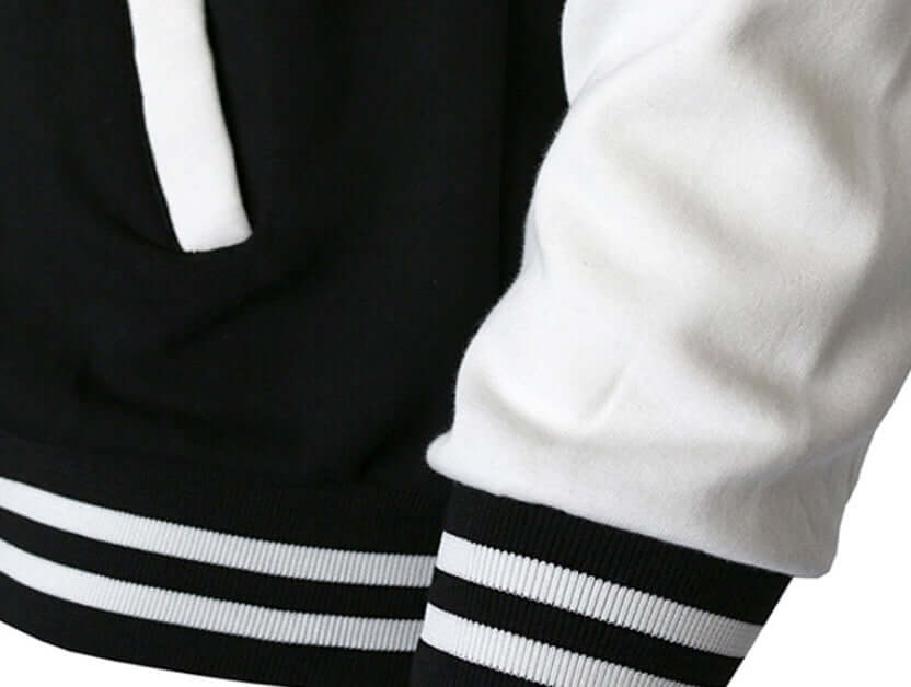 Close-up of a baseball jacket sleeve featuring black and white color blocking with ribbed cuffs.