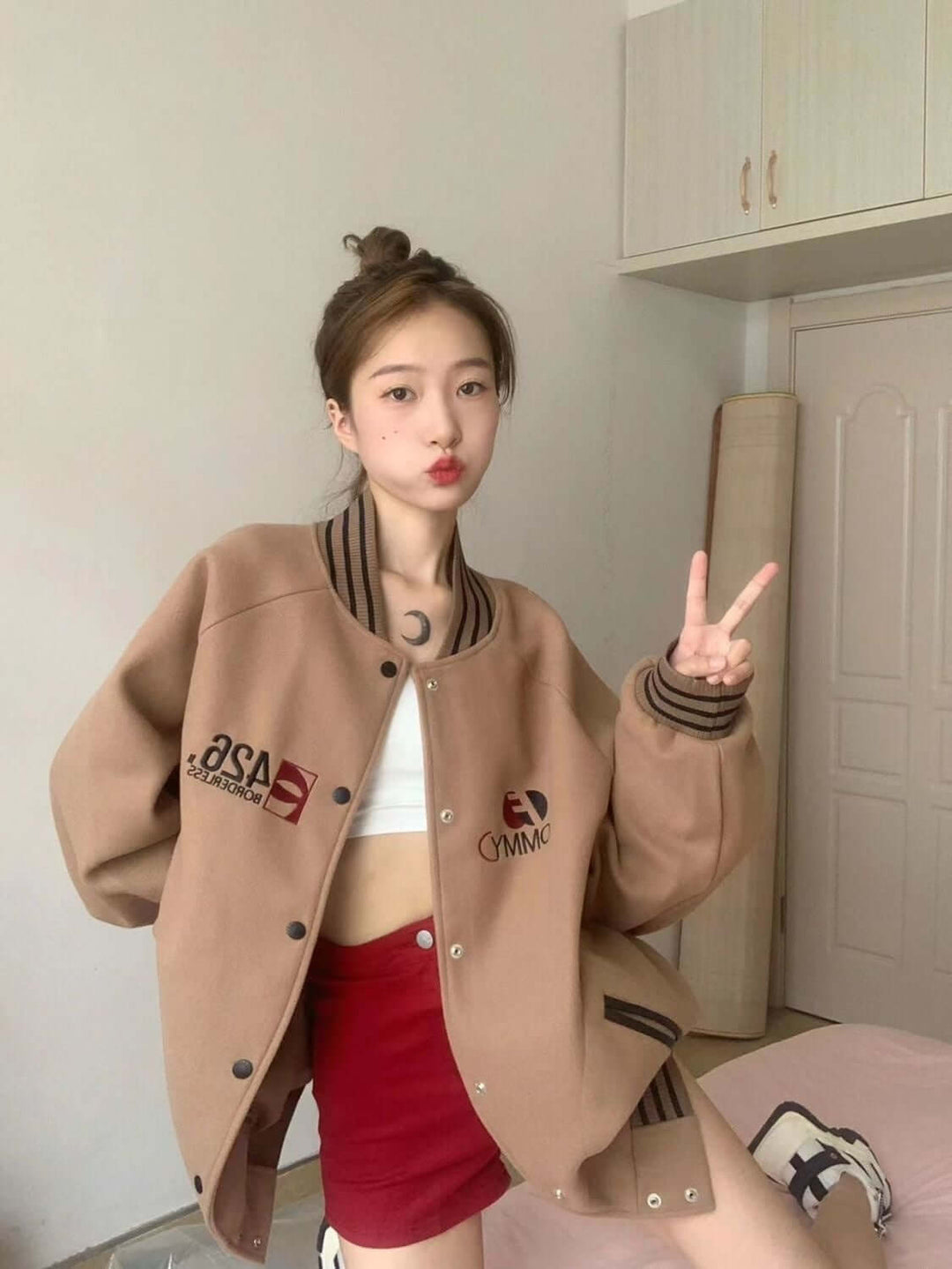 Trendy woman wearing a stylish brown autumn commuter jacket over a white crop top and red skirt.