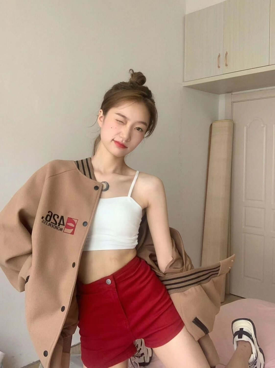 Trendsetting woman wearing a stylish brown autumn commuter jacket over a white top and red shorts.