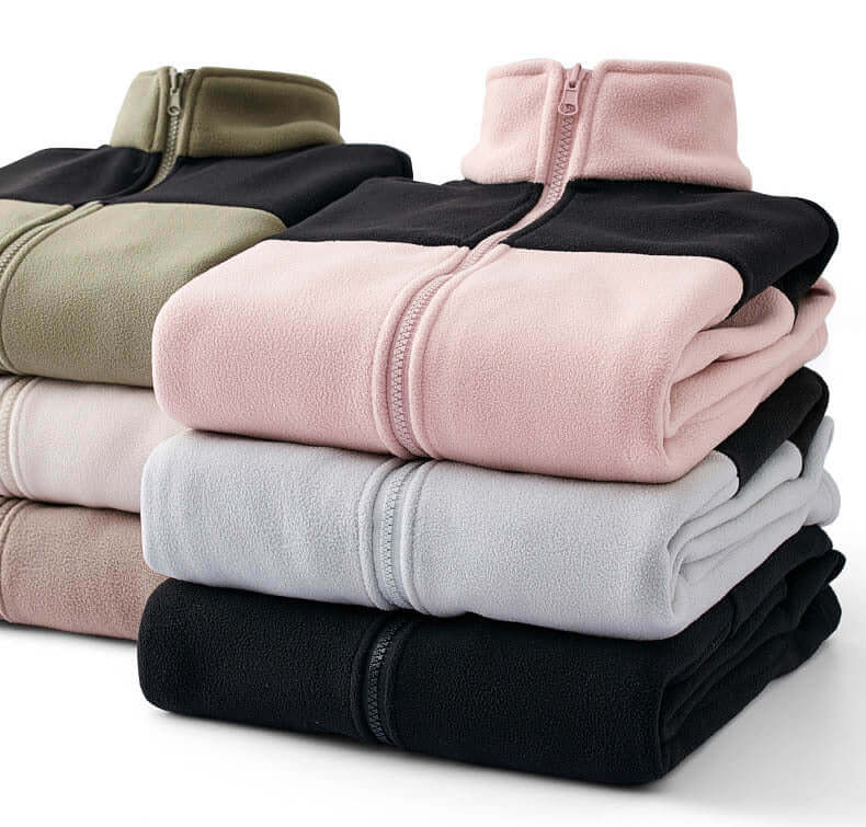 Stack of colorblock fleece jackets in black, pink, grey, and olive, perfect for layering and outdoor activities.
