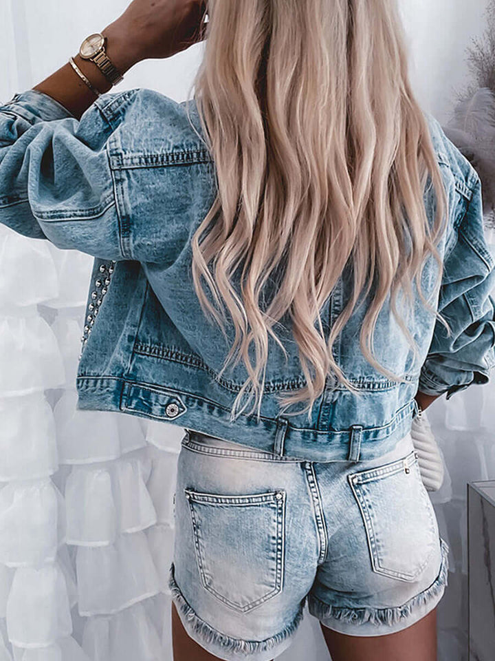 Back view of a woman wearing a women's autumn street denim jacket with long hair and denim shorts.